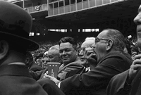 LBJ eating a fistful of popcorn at a baseball game.